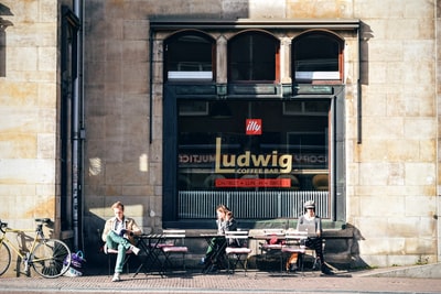 三个人坐在户外椅子前面路德维希咖啡馆

